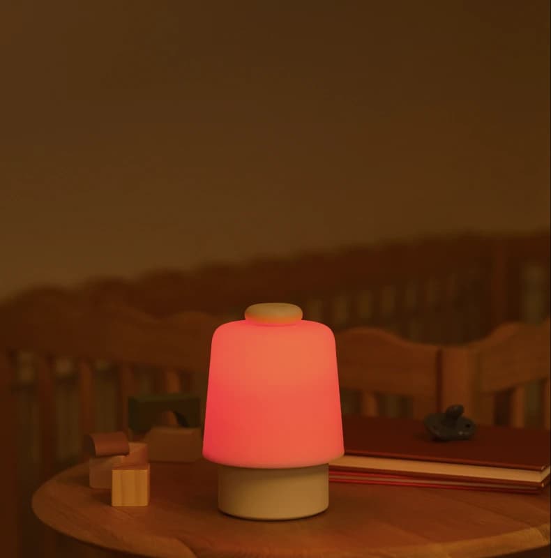 Lit up Hatch Baby on a nursery table next to some baby toys